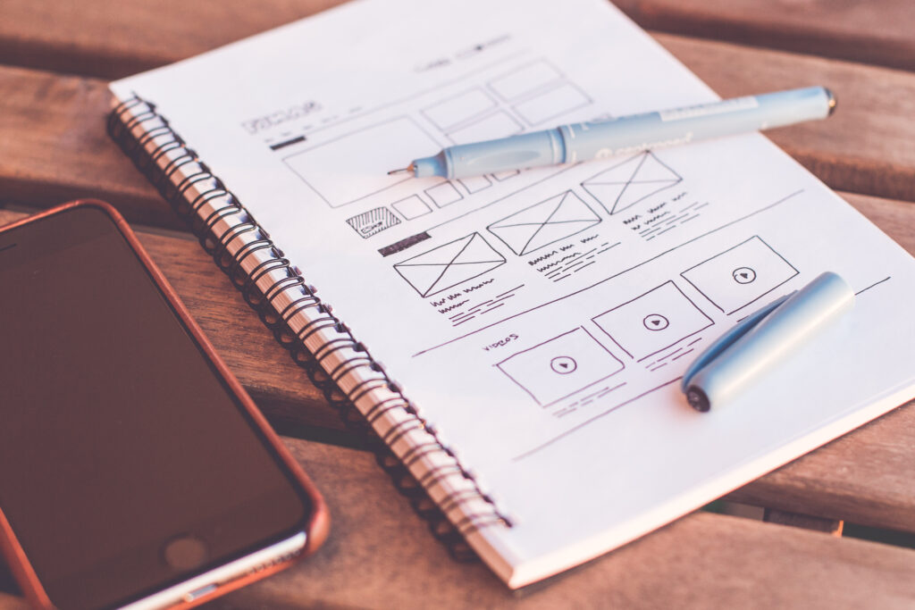Closeup photo of paper and pen UX design sketching and smartphone on the wooden desk