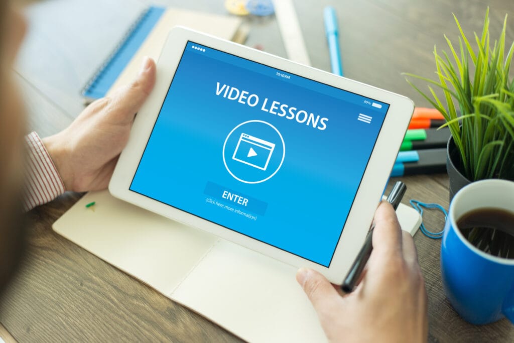 Tableta que muestra el texto «lección de vídeo en línea» localizado en la lengua materna del alumno